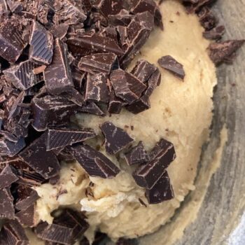 Chocolate chunks on top of dough in mixing bowl