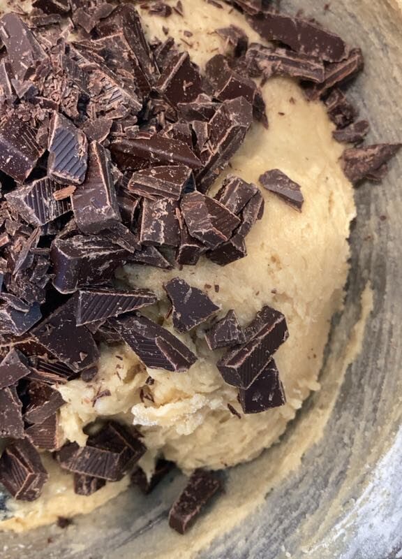 Chocolate chunks on top of dough in mixing bowl