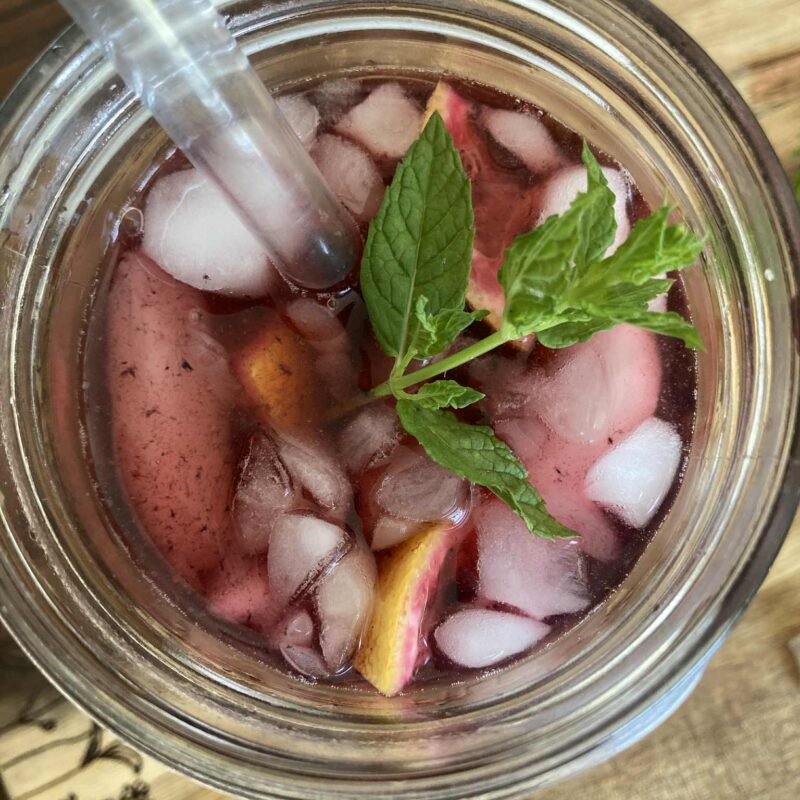 Blackberry water with crushed ice, mint and lemon in a mason jar