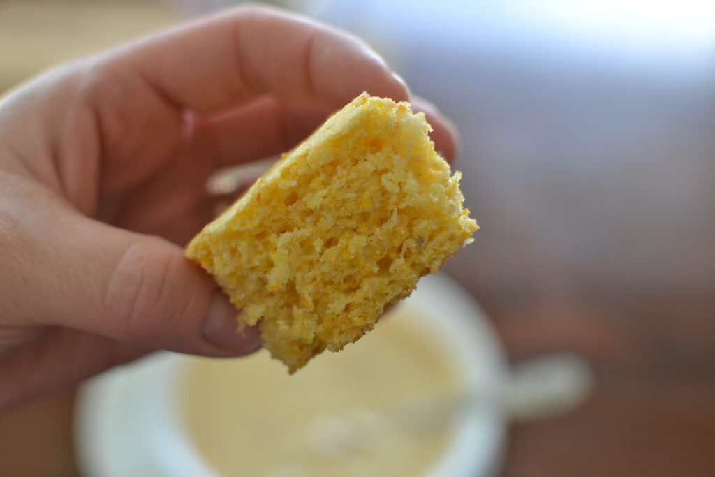 Hand holding a piece of yellow cornbread