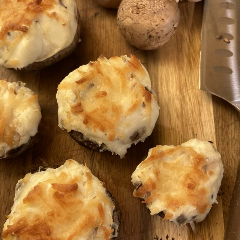 Cream cheese stuffed mushrooms on a cutting board