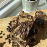 Square cookies drizzled in chocolate stacked up on a cutting board